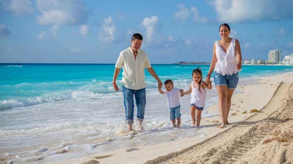 Famille marchant ensemble le long du rivage pendant une séance photo du matin à Playa del Carmen