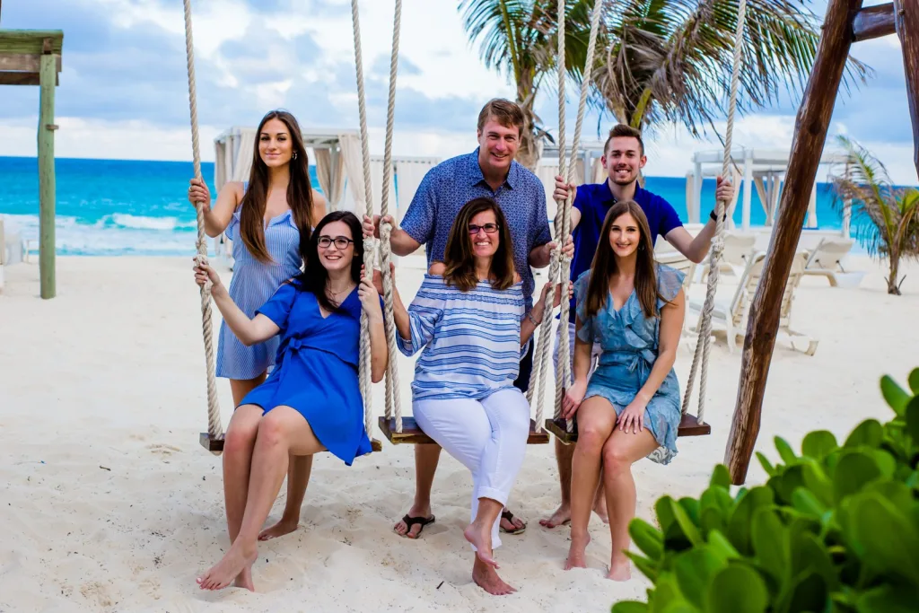 Padres e hijos riendo juntos en la arena abierta durante una sesión de fotos familiar en Playa del Carmen