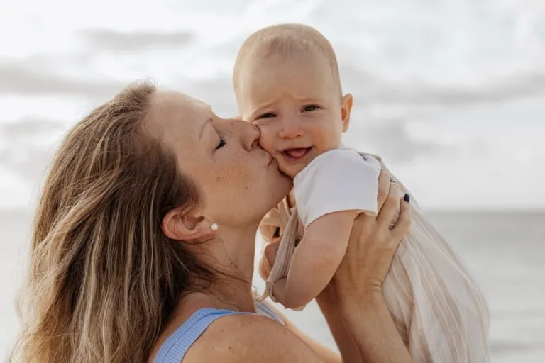Mother holding her baby on the sand during an early-morning family photo session in Playa del Carmen